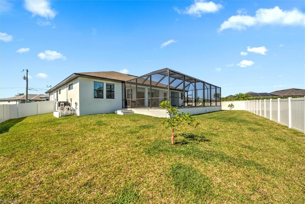 Back of house with a patio, glass enclosure, and a yard