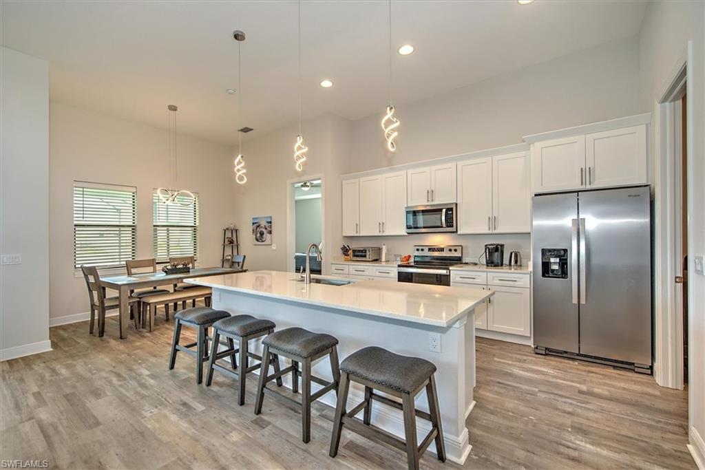 Kitchen featuring light hardwood / wood-style floors, stainless steel appliances, a kitchen island with sink, sink, and pendant lighting