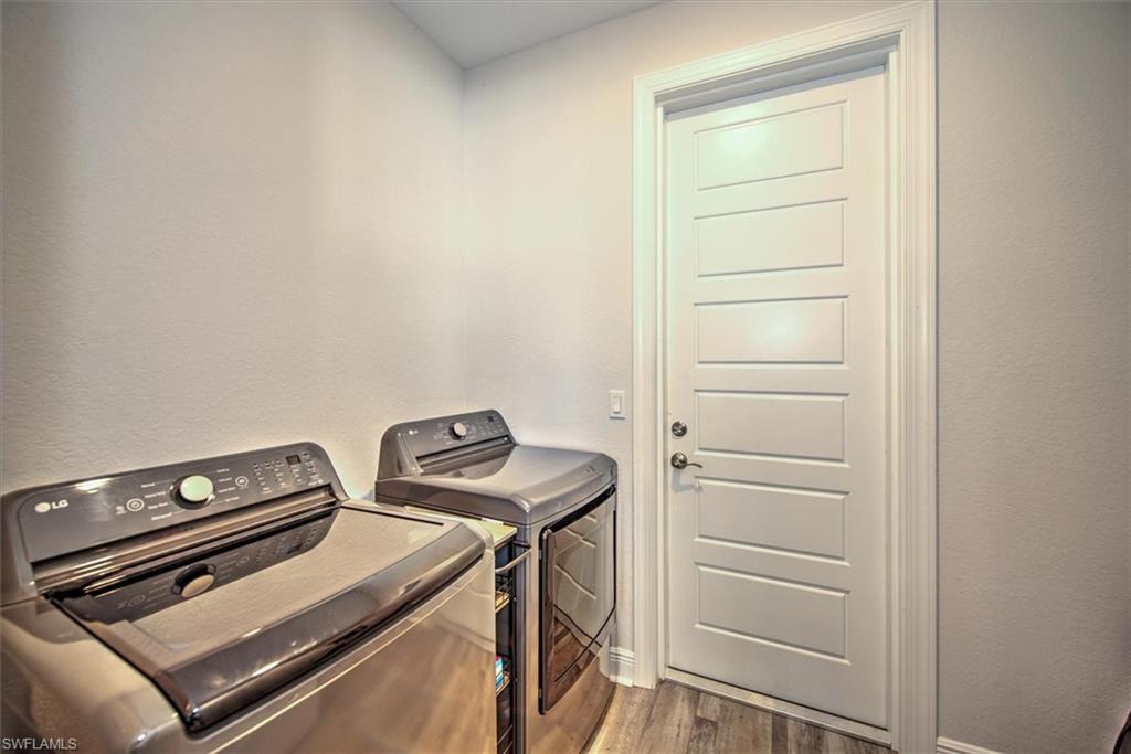 Washroom with washer and dryer and hardwood / wood-style flooring