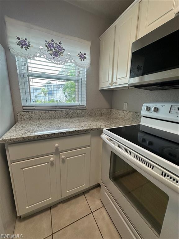 Kitchen featuring light-toned cabinetry, light-toned countertops, and tile flooring