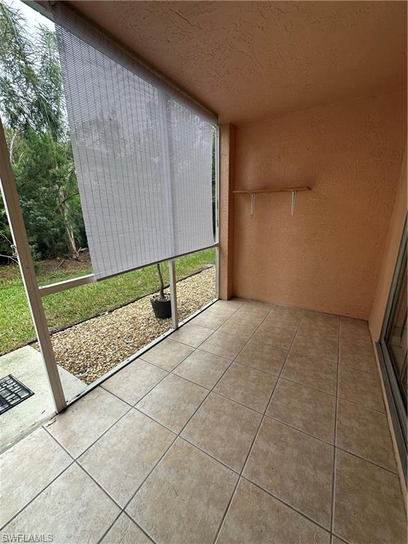 Screened patio featuring neutral-toned tile flooring and textured stucco walls