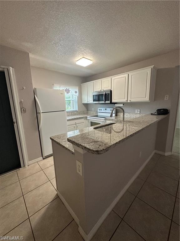 Kitchen featuring granite countertops, white cabinetry, stainless steel microwave, and tile flooring