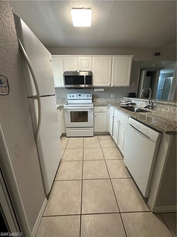 Kitchen featuring white cabinetry, granite-finish countertops, and a full suite of white appliances