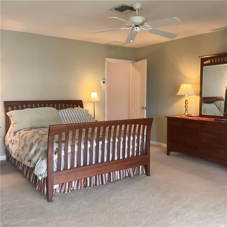 Primary bedroom with queen size bed, ceiling fan and carpet