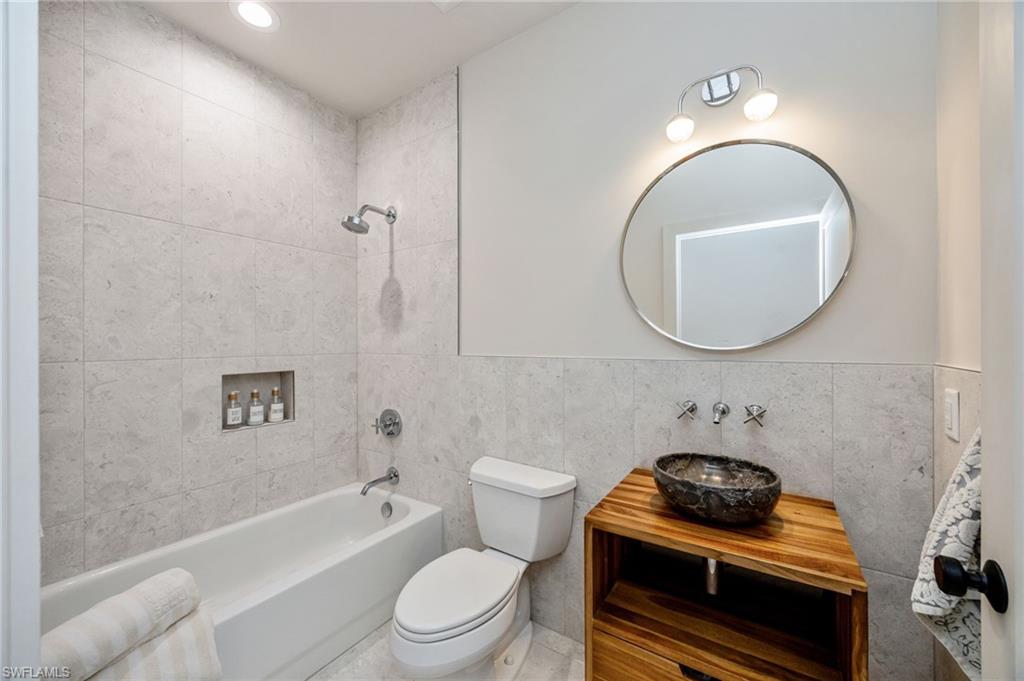 Beautifully updated guest bathroom with a custom teak vanity, elegant fixtures, and contemporary style