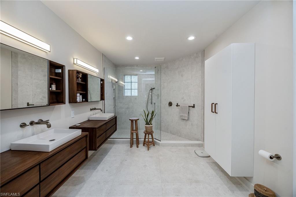 Stunningly reimagined primary bathroom showcasing contemporary style with teak vanities, premium finishes, and exceptional craftsmanship