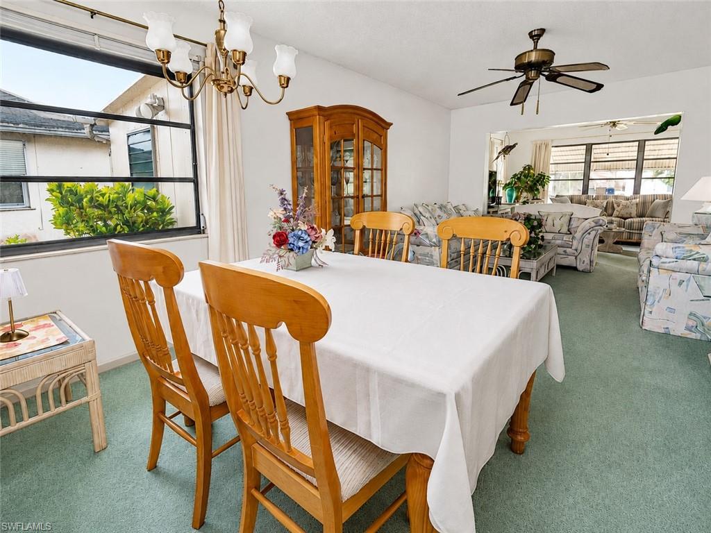 Dining area with soft green carpeting and a brass chandelier