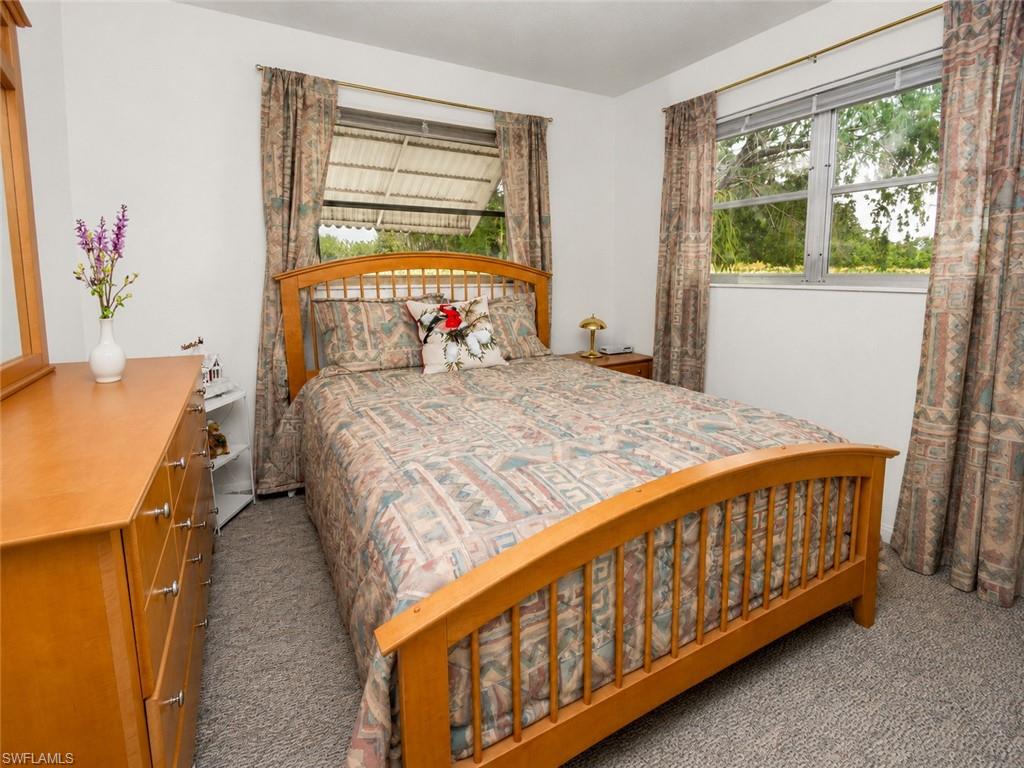 Gray carpeted flooring with a light wood-finish dresser featuring silver-toned hardware