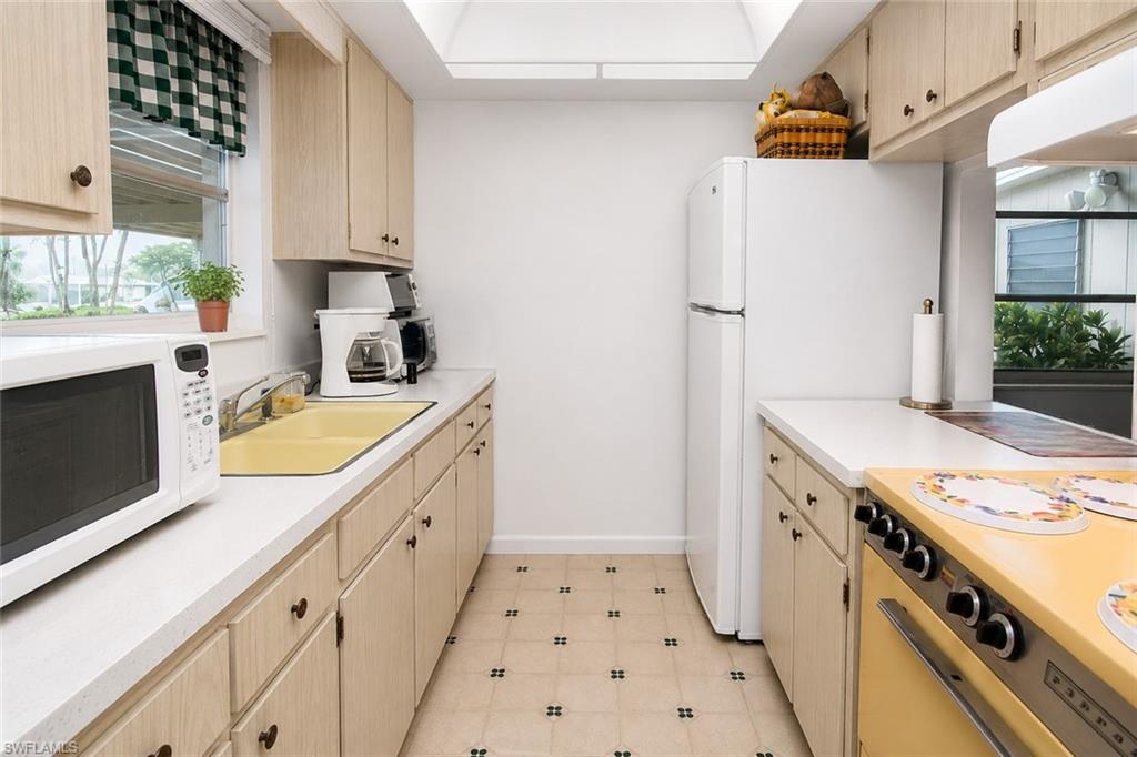 Galley kitchen featuring light wood-finish cabinetry, white countertops, and patterned floor tiling