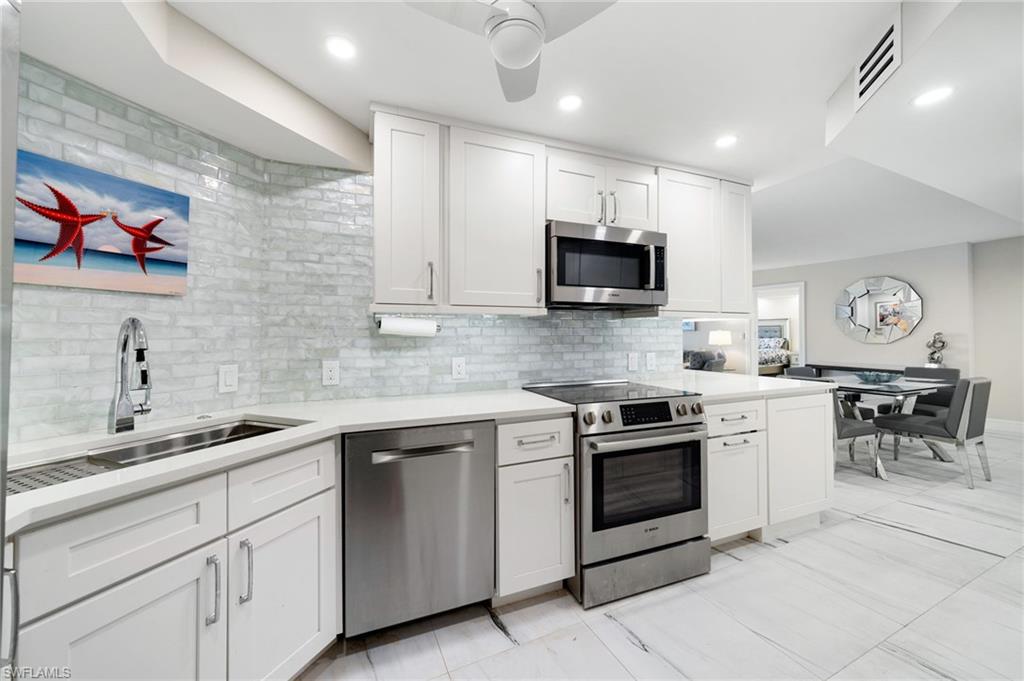 Kitchen featuring tasteful backsplash, light tile patterned flooring, appliances with stainless steel finishes, ceiling fan, and white cabinets