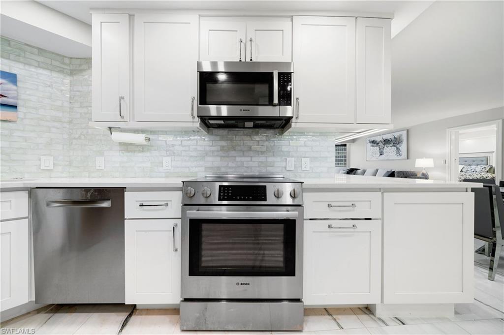Kitchen with white cabinets, stainless steel appliances, and decorative backsplash