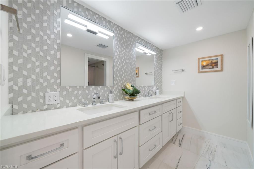 Bathroom with double sink vanity, tile patterned flooring, and backsplash