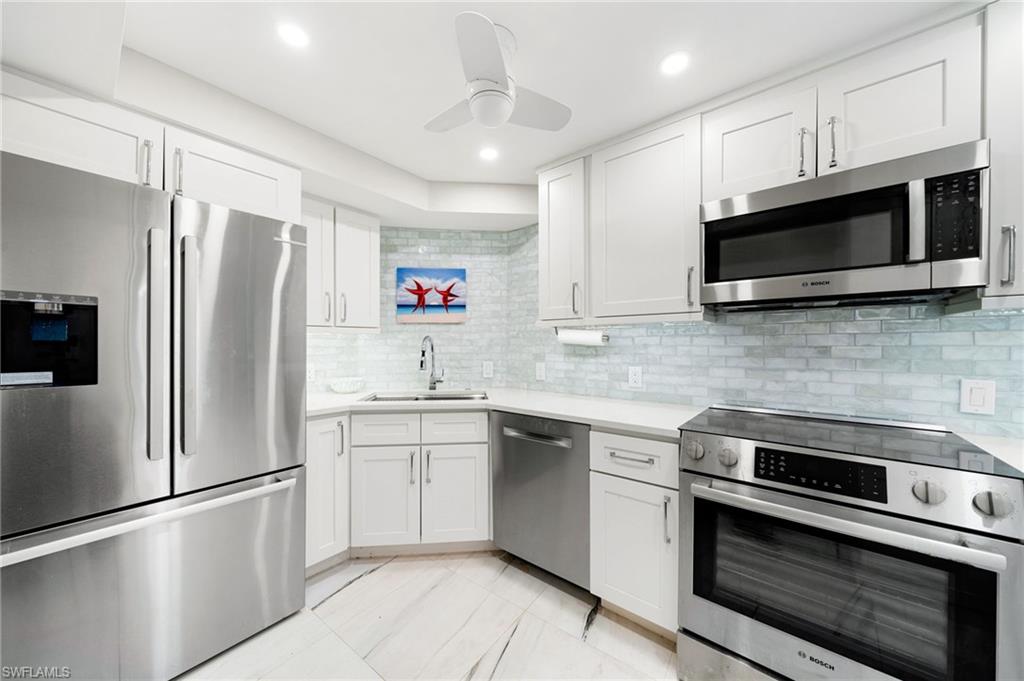 Kitchen featuring decorative backsplash, appliances with stainless steel finishes, sink, and white cabinets