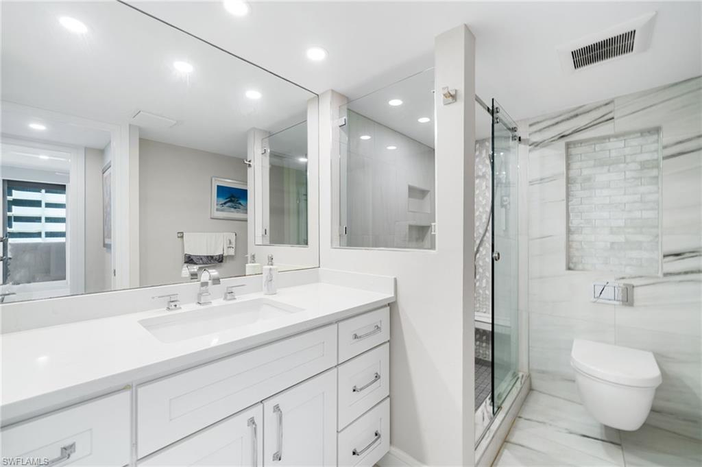 Bathroom with walk in shower, vanity, tile patterned flooring, and toilet