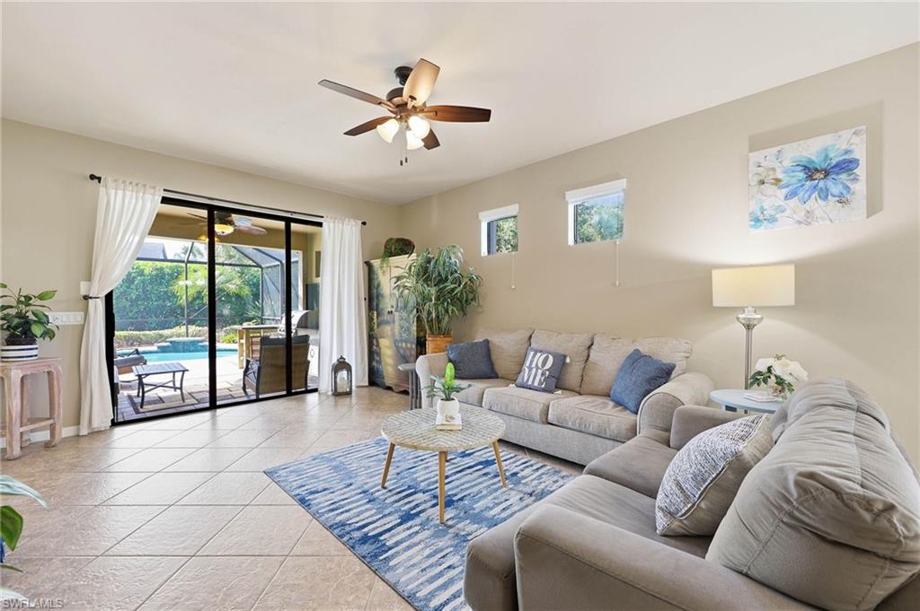 This open-concept great room features triple sliding glass doors that open to an expansive covered lanai, offering scenic views of the pool and a private rear yard.