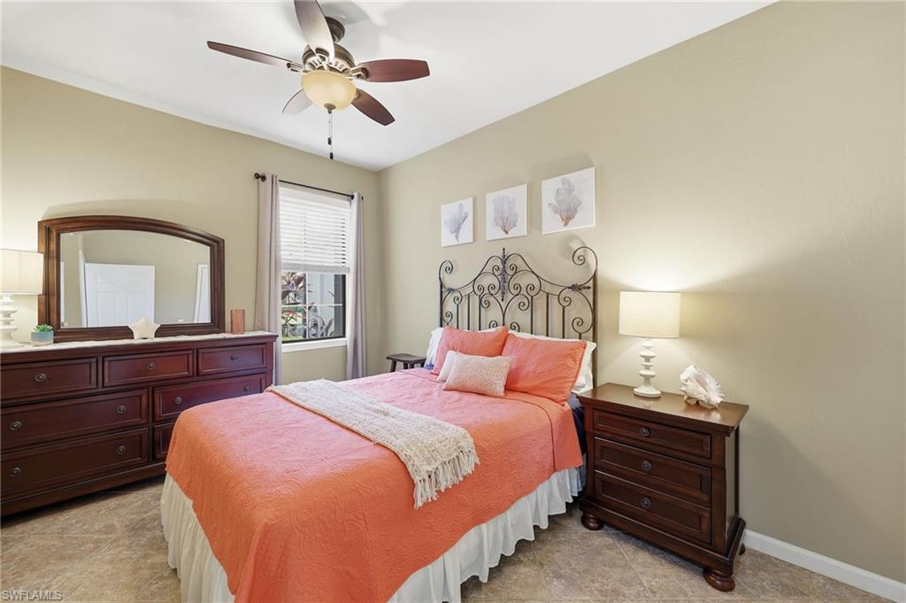 This bright guest bedroom features neutral wall tones that complement the tile flooring, as well as a large walk-in closet providing ample storage space.