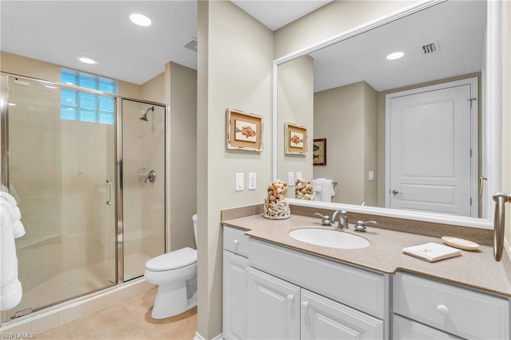 Guest bathroom featuring vanity, toilet, tile floors, and a walk-in shower