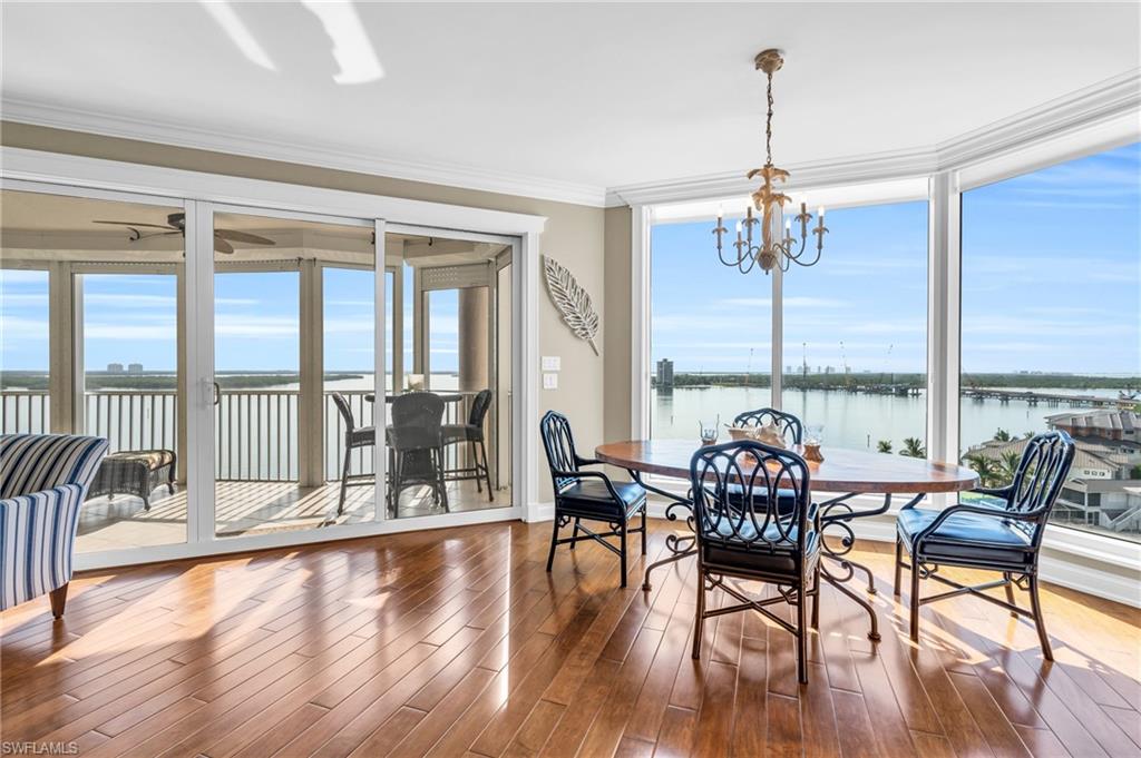 Dining room with crown molding, ceiling fan with notable chandelier, dark hardwood / wood-style floors, and a water view