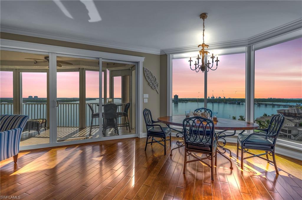 Dining space featuring ornamental molding, ceiling fan with notable chandelier, hardwood / wood-style floors, and a water view