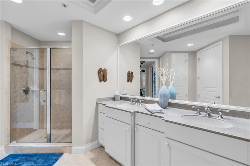 Main bathroom with large walk in shower, double vanity, crown molding, and tile floors