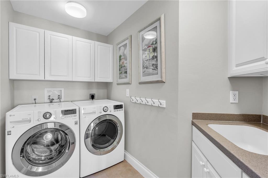 Laundry room featuring light tile patterned floors, cabinets, sink, and independent washer and dryer