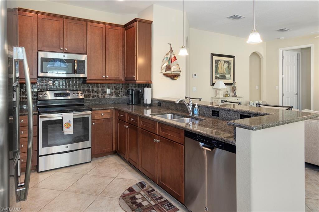 Kitchen featuring light tile patterned floors, sink, stainless steel appliances, and decorative backsplash