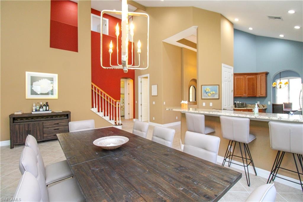 Dining space with light tile patterned flooring and high vaulted ceiling