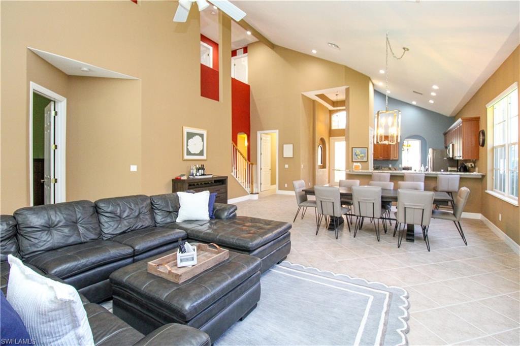 Tiled living room with ceiling fan and high vaulted ceiling