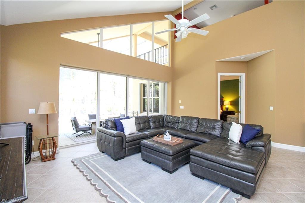 Living room featuring light tile patterned flooring, high vaulted ceiling, and ceiling fan
