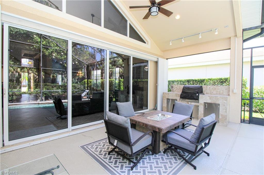 Sunroom / solarium with lofted ceiling, ceiling fan, track lighting, and a wealth of natural light