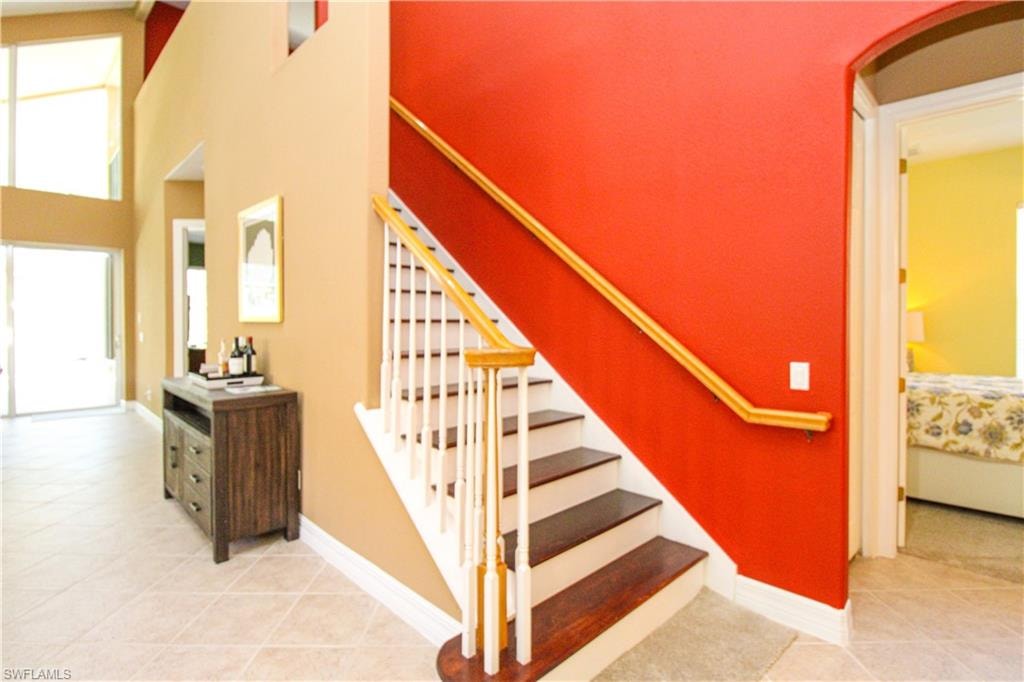 Stairs with light tile patterned floors and a high ceiling