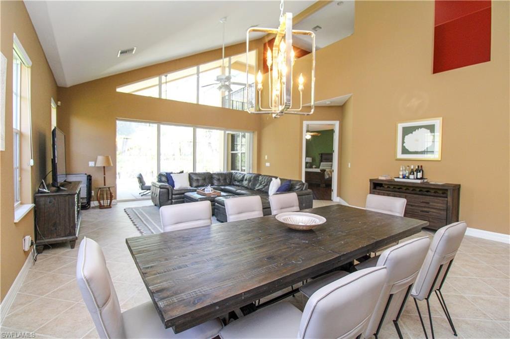 Tiled dining area with ceiling fan with notable chandelier and high vaulted ceiling