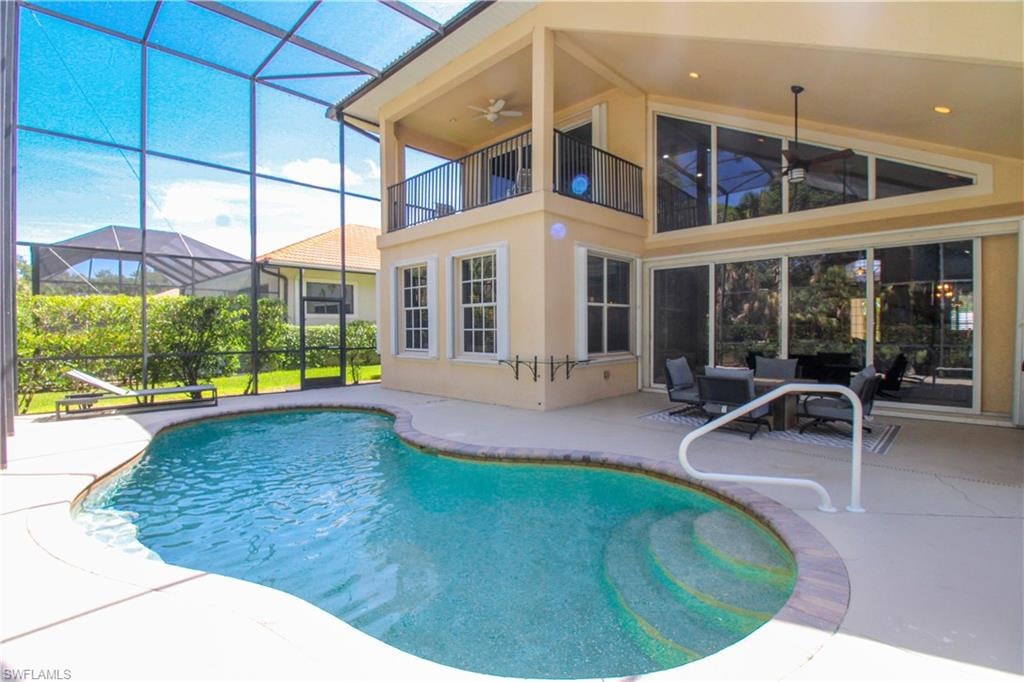 View of pool with an outdoor hangout area, glass enclosure, a patio area, and ceiling fan