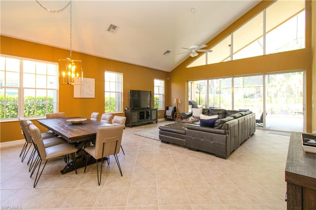 Tiled dining area featuring beam ceiling, ceiling fan with notable chandelier, and high vaulted ceiling