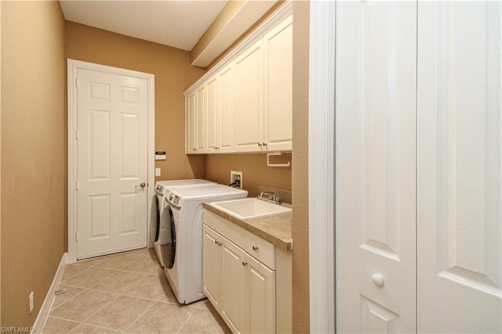 Laundry area featuring sink, cabinets, washer and dryer, and light tile patterned floors
