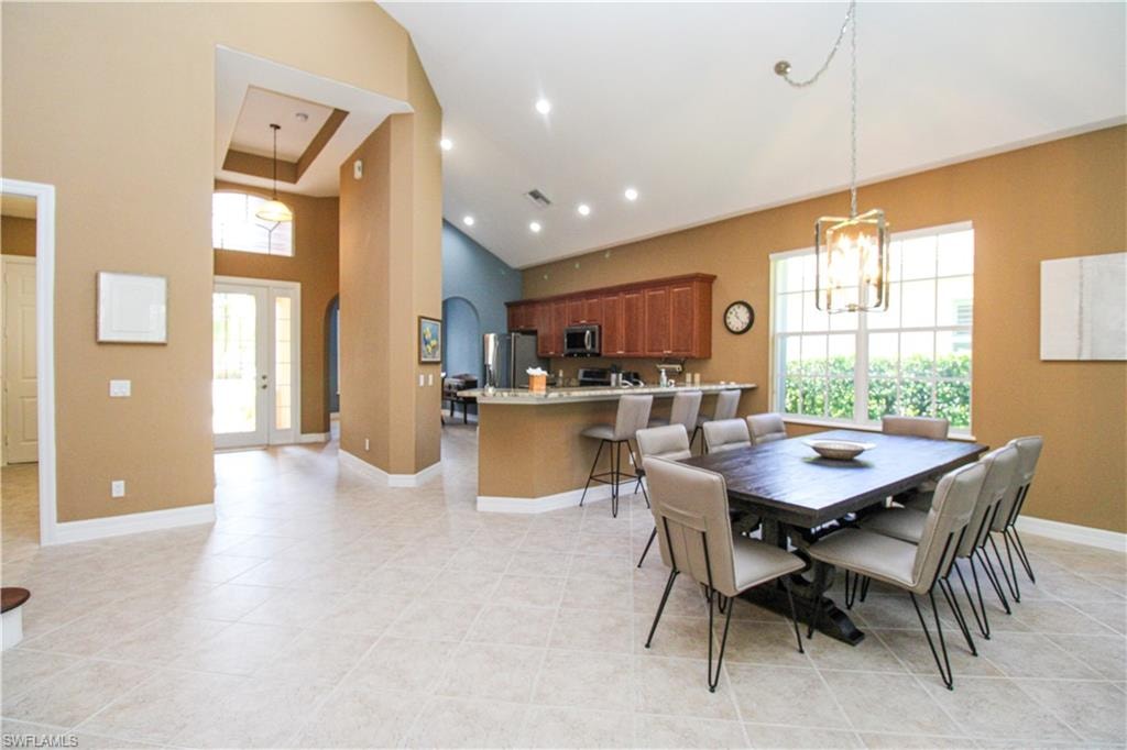 Dining area with an inviting chandelier, light tile patterned floors, and high vaulted ceiling