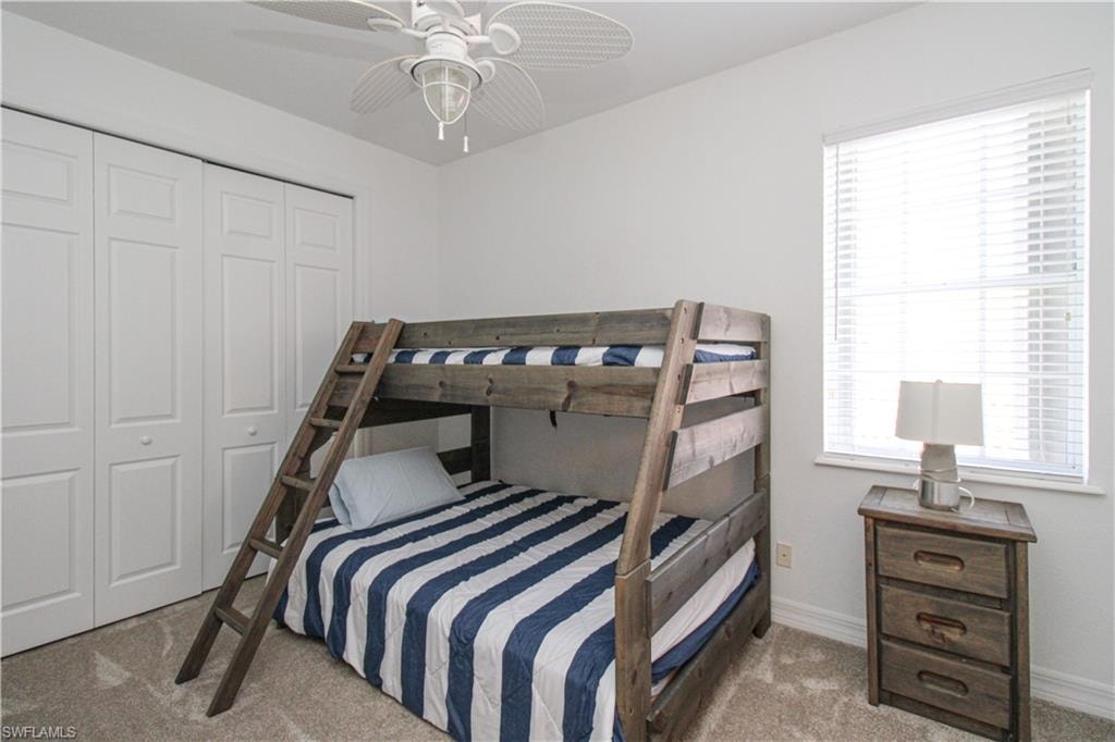 Carpeted bedroom featuring a closet and ceiling fan