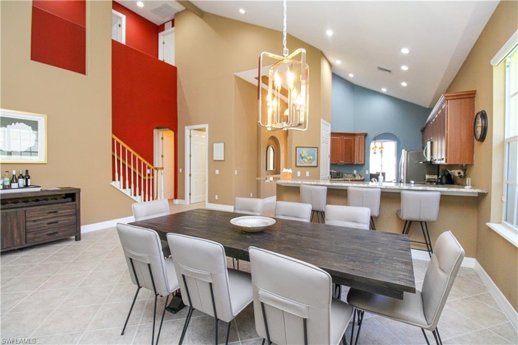 Living room featuring light tile patterned flooring, high vaulted ceiling, and ceiling fan