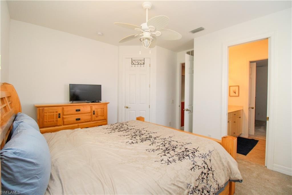 Bedroom featuring light carpet, ceiling fan, and connected bathroom
