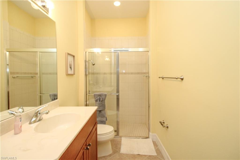 Bathroom featuring tile patterned flooring, a shower with door, toilet, and vanity