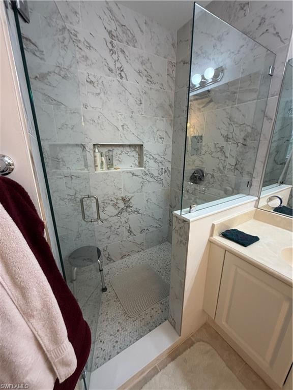 Shower enclosure featuring floor-to-ceiling marble-patterned tile, a built-in shower niche, and a seamless glass partition