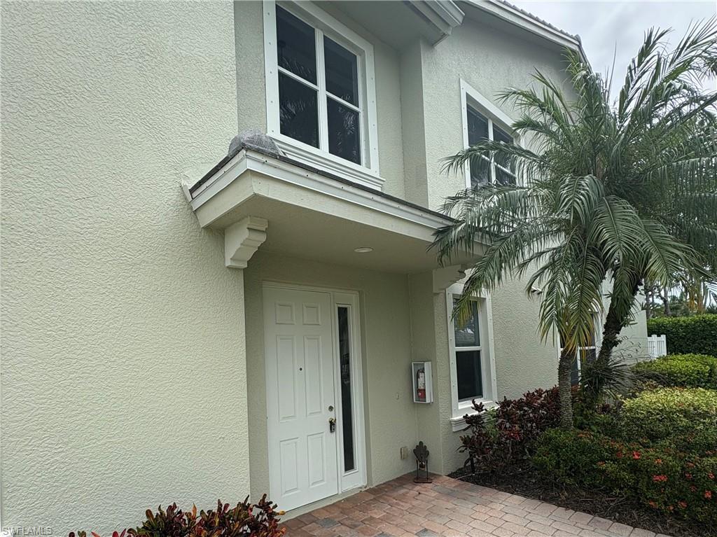 Stucco exterior with a covered entry featuring a white panel door and sidelight