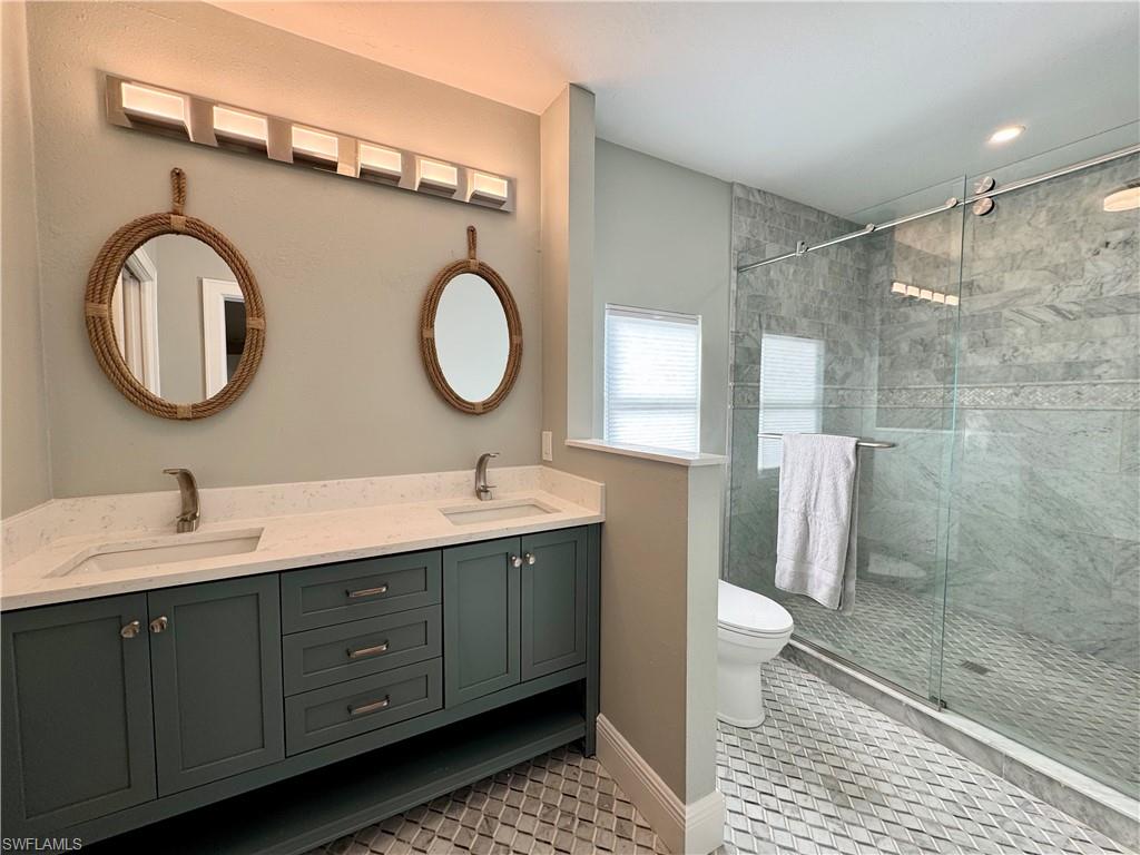 Bathroom with tile patterned flooring, vanity, toilet, and walk in shower