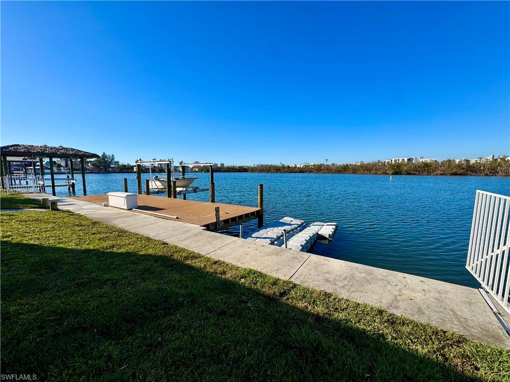 View of dock with a water view and a lawn