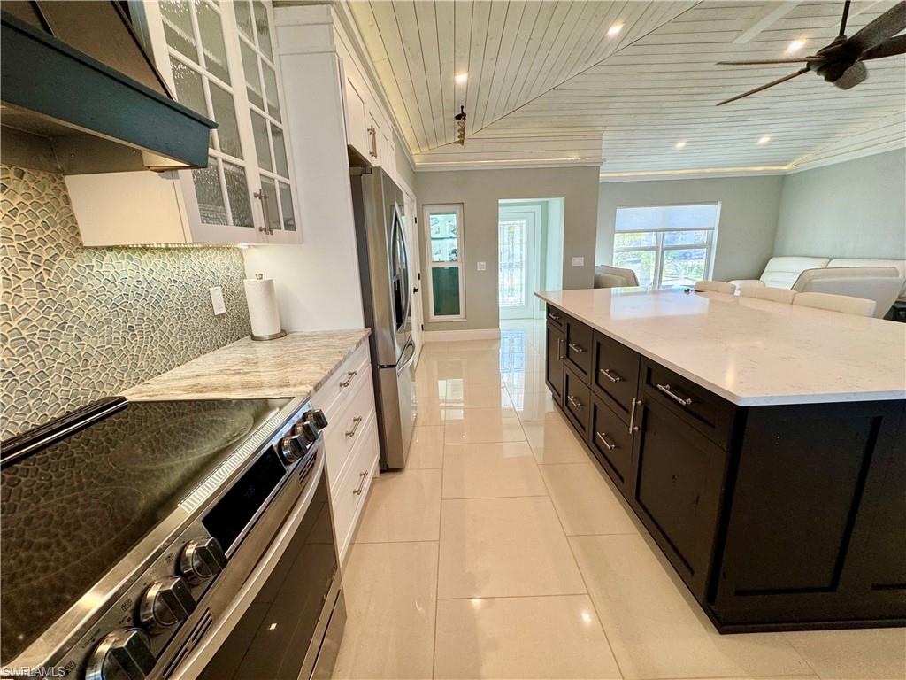 Kitchen featuring backsplash, white cabinets, ventilation hood, wood ceiling, and stainless steel appliances