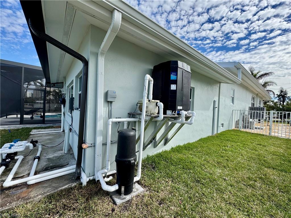 View of side of property featuring a yard and glass enclosure