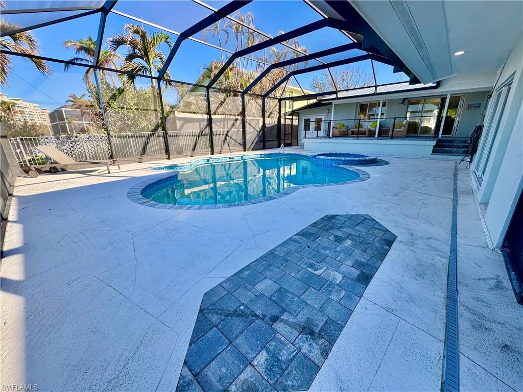 View of swimming pool with glass enclosure and a patio area