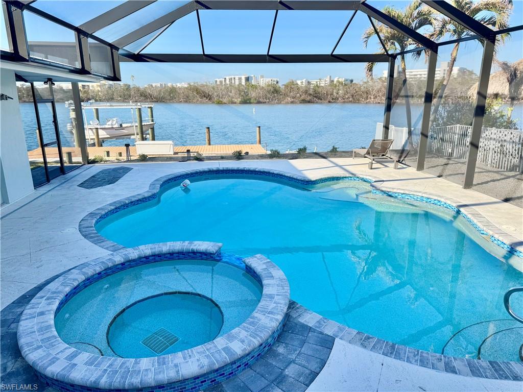 View of swimming pool with a Bayview, a boat dock, a lanai, an in ground hot tub, and a patio