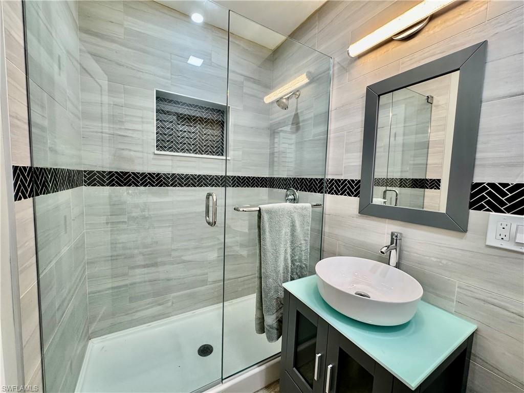 Bathroom featuring vanity, an enclosed shower, and tile walls