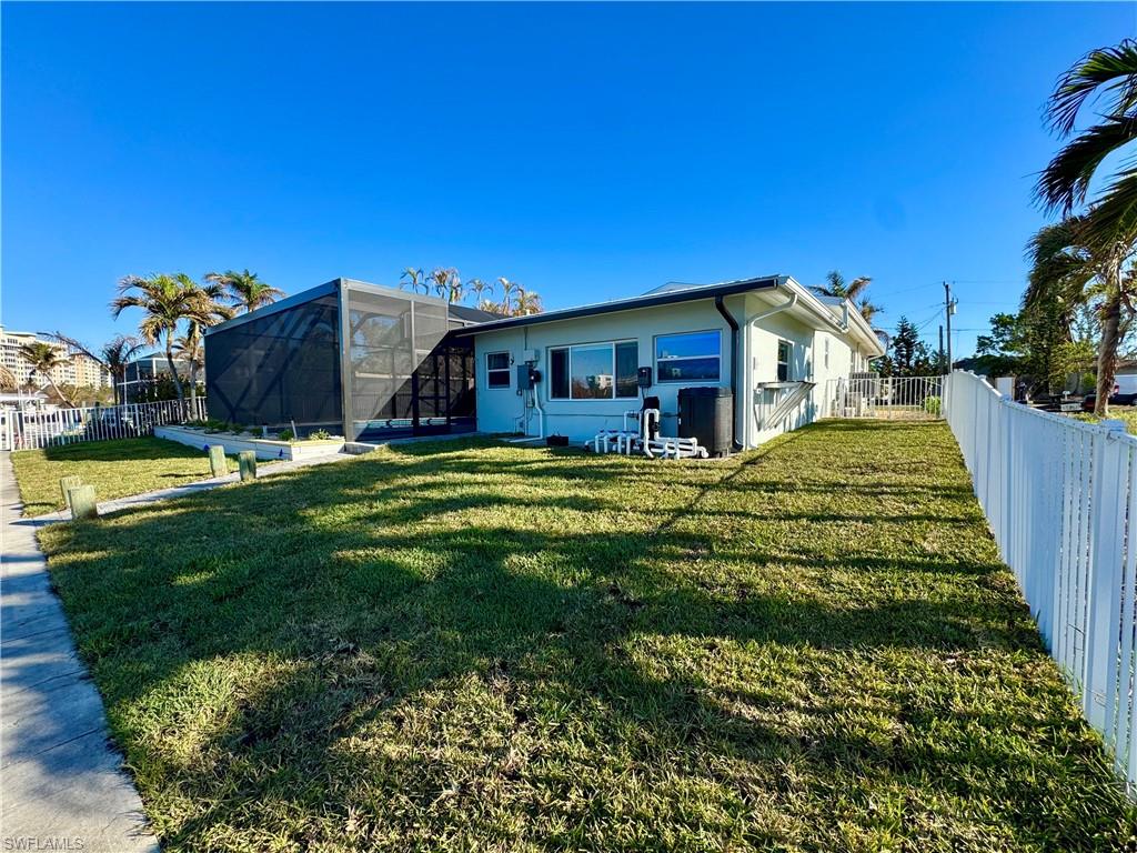 Back of house featuring glass enclosure and a yard